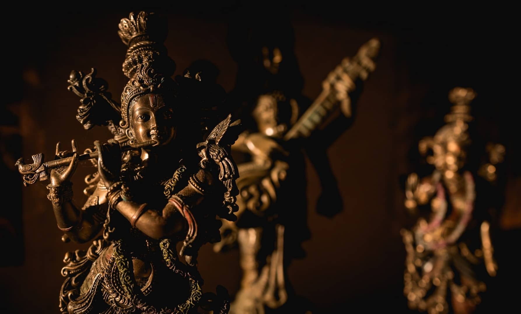 Statuete de bronz ale zeităților, luminate cald pe un altar