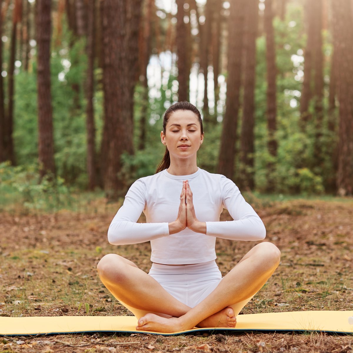 Practicant de yoga în postură de meditație, cu palmele împreunate.